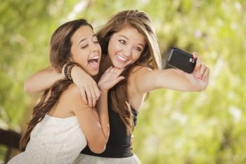 Two Attractive Mixed Race Girlfriends Taking Self Portrait with Their Phone Camera Outdoors.