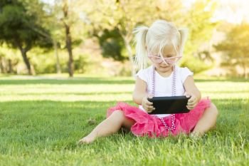 Cute Little Girl Sitting In Grass Playing With Cell Phone.