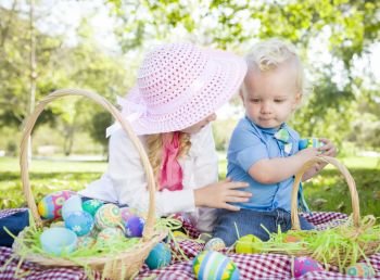 Cute Young Brother and Sister Enjoying Their Easter Eggs Outside in the Park Together.
