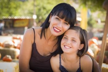 Attractive Mother and Baby Daughter Portrait in a Rustic Ranch Setting at the Pumpkin Patch.
