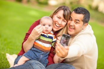 Happy Mixed Race Parents and Baby Boy Taking Self Portraits at the Park.