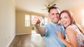 Young Military Couple with House Keys In Empty Room of New Home.
