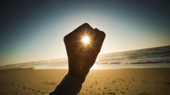 Female hand holding the sun on a signal of hope and strength