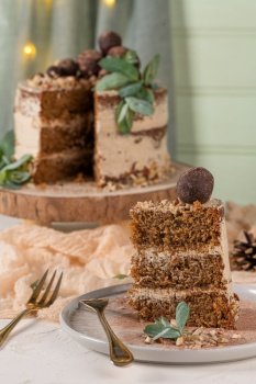 Slice of delicious naked chocolate and hazelnuts cake on table rustic wood kitchen countertop.