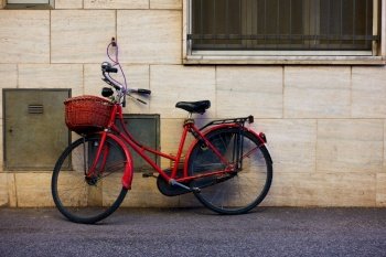 Red bicycle with basket near wall in Rimini, Italy