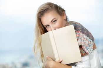 Nice calm female with pleasure reads a book at home, authentic natural beauty of a young female enjoying good novel about love