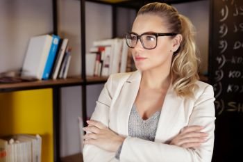 Portrait of a pretty serious woman wearing eyeglasses, young entrepreneur working in the office, successful career of a young businesswoman