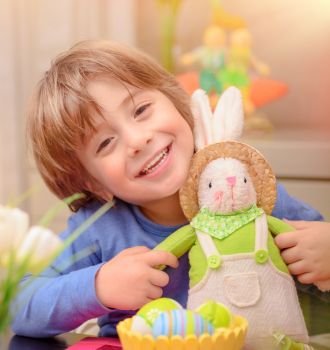 
Portrait of cute happy little boy play with decorative bunny toy at home, traditional Easter symbol, having fun on spring religious holiday