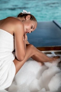 Pretty girl enjoying warm nice bath and amazing seaview, relaxation on the luxury spa resort, summer vacation on Maldives