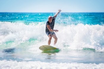 Surfer enjoying high waves in bright sunny day, active lifestyle, extreme water sport, summer time activities, recreation on the beach