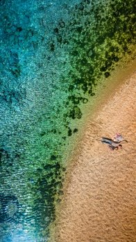Drone View Photo of a Young Mother and herLittle Son Lying Down on Beautiful Golden Sand on the Tropical Island. Happy Family Enjoying Beach. Vertical Panorama. Flat Lay. 