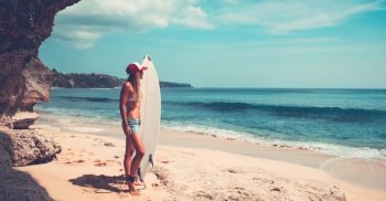 Sportive woman with surfboard on beautiful sandy coast, active hobby, waiting for a good waves, enjoying summer vacation on the beach
