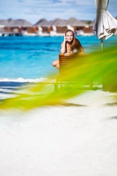 Beautiful woman on the beach, wearing white bikini and taking sun bath on the sunbed, photo with copy space, enjoying summer holidays on Maldive islands