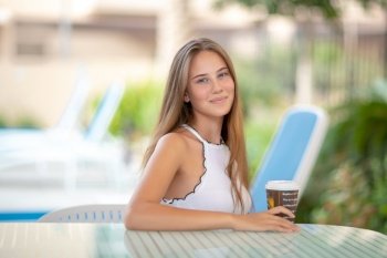 Portrait of a pretty woman sitting in outdoors cafe with morning coffee, relaxing on the beach resort, happy summer vacation