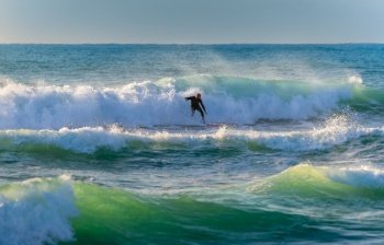 Surf. Picture of a Man Riding a Surfboard on the Crest of a Wave. Summertime Activity. Extreme Water Sport. Enjoying Summer Vacation on the Sea. 