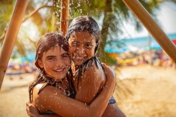 Portrait of a two little girls standing together under outdoor shower on the beach, best friends with pleasure spend summer holidays near the sea, summer camp fun, happy kids