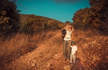 Young mother with little son walking on the trail in the mountains, camping in wild nature, active sportive family