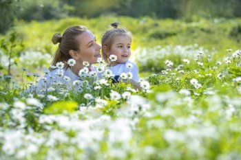 Adorable Little Boy with his Beautiful Mom Enjoying Fresh Daisy Field. Leisure Time in Countryside. Spending Summer Holidays Together outdoors.. Having Fun in Daisies Field