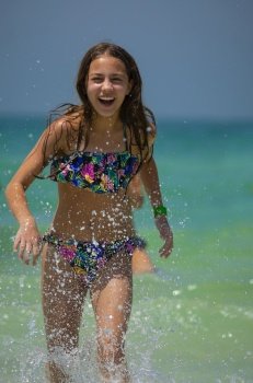 Cute Teen Girl Runs Out of the Sea on the Beach. Splashing the Water and Laughing. Happy Summer Vacation on the Beach Resort.. Happy Girl on the Beach