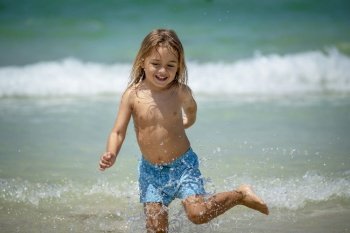 Portrait of a Cute Little Boy Running in the Water Making Splashes. Happy Child Enjoying Active Summer Holidays on the Beach Resort.. Happy Little Boy on the Beach