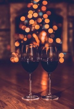 Two Glasses of a Red Wine on Festive Bokeh Background. Romantic Evening Near Christmas Tree at Home. Stylish New Year Greeting Card.. Romantic Christmas Dinner