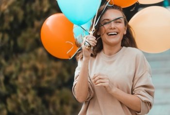 Portrait of a Beautiful Smiling Female with Colorful Air Balloons Having Fun Outdoors. Enjoying Birthday Party in Warm Sunny Day on Backyard.. Birthday Girl with Colorful Balloons Outdoors