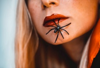 Halloween Makeover Fashion Ideas. Beautiful Female Face with Spiders. Holiday Makeup. Bright Red Lipstick. Blond Hair. Girl Model. Lips Closeup.. Halloween Fashion Portrait