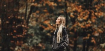 Nice Blond Woman With Closed Eyes Enjoying Beautiful Autumn Nature in the Park. Pretty Girl over Blurry Autumnal Foliage Background.. Beautiful Woman in Autumn Park