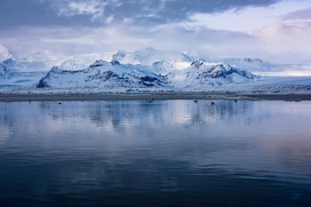 Beautiful Winter Landscape. Glacial Lake with Icebergs and Birds in it. Gorgeous Great Mountains Covered with Snow. Vantajokull Jokulsarlon. Iceland.. Glacial Lake with Icebergs