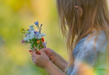 Side View on a Nice Little Child with Long Hair Enjoying Aroma of a Fresh Wild Flowers. Happy Kid in Spring Garden.. Happy Child in Spring Garden
