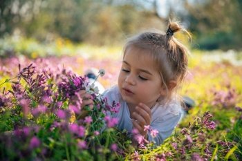 Portrait of a Beautiful Little Child Playing on Floral Field. Enjoying Pink Gentle Wild Flowers in Bright Sunny Day. Happy Life in Countryside.. Happy Child on Flowers Field