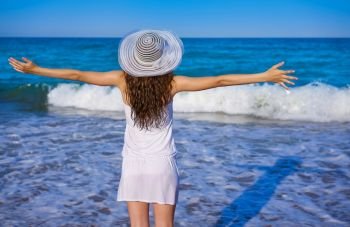 Girl with beach hat in sea open arms with summer white dress