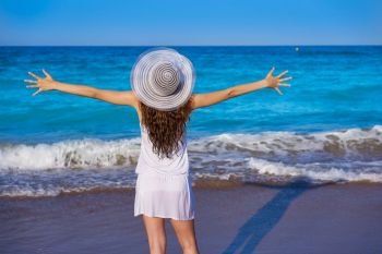 Girl with beach hat in sea open arms with summer white dress