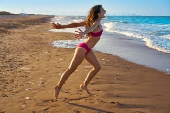 Bikini girl running to the beach shore water of Mediterranean sea