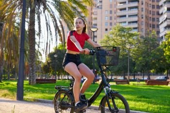 Girl riding e-bike in a city park with red t-shirt foldable ebike