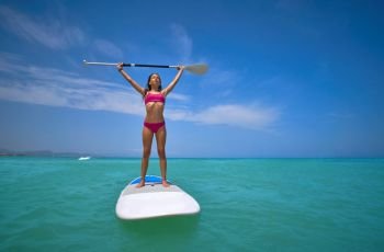 Girl standing on paddle surf board SUP in summer