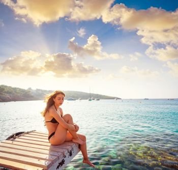 Ibiza bikini girl relaxed at Portinatx beach  pier sunset in Balearic Islands