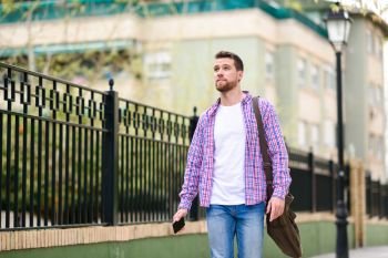 Young bearded man walking in urban background. Traveler wearing casual clothes. Lifestyle concept.