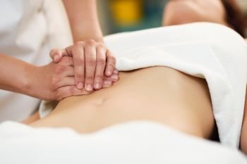 Therapist applying pressure on belly. Woman receiving massage at spa salon. Hands massaging female abdomen