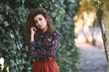 Beautiful young arabic woman with black curly hairstyle. Arab girl wearing casual clothes in the street.. Beautiful young arabic woman with black curly hairstyle.