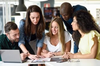 Five young people studying on white desk. Beautiful women and men working together wearing casual clothes. Multi-ethnic group.