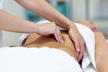 Female patient is receiving treatment by professional osteopathy therapist. Woman having abdomen massage in a physiotherapy center.. Woman having abdomen massage by professional osteopathy therapist