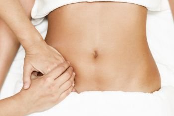Top view of hands massaging female abdomen.Therapist applying pressure on belly. Woman receiving massage at spa salon. Hands massaging female abdomen.Therapist applying pressure on belly.