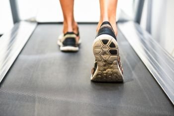 Male muscular feet in sneakers running on the treadmill at the gym. Concept for fitness, exercising and healthy lifestyle.