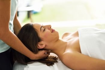 Young caucasian smiling woman receiving a head massage in a spa center with eyes closed. Female patient is receiving treatment by professional therapist.. Young smiling woman receiving a head massage in a spa center.