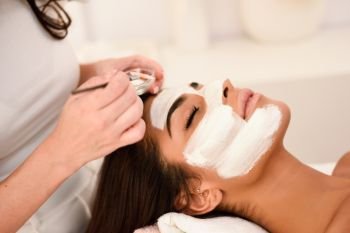 Aesthetics applying a mask to the face of a beautiful woman in modern wellness center. Beauty and Aesthetic concepts.. Aesthetics applying a mask to the face of a beautiful woman
