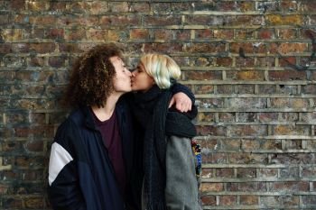 Young couple enjoying Camden town in front of a brick wall typical of London, UK. Man and woman kissing. Young couple enjoying Camden town in front of a brick wall typical of London