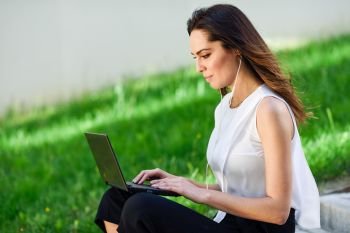 Middle-age businesswoman working with her laptop computer sitting on urban steps outdoors.. Young woman working with her laptop computer sitting on the floor.