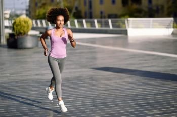 Black woman, afro hairstyle, running outdoors in urban road. Young female exercising in sport clothes.. Black woman, afro hairstyle, running outdoors in urban road.