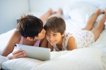 Middle-age mother with her eight years daughter using digital tablet in bedroom. Funny mom and lovely little girl are having fun on the bed.. Middle-age mother with her eight years daughter using digital tablet in bedroom.
